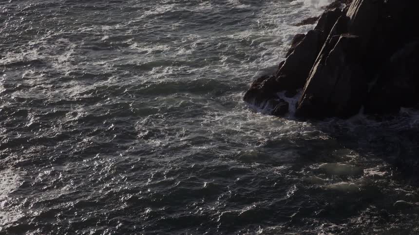 Rocky ocean cliff with light waves due to the wind