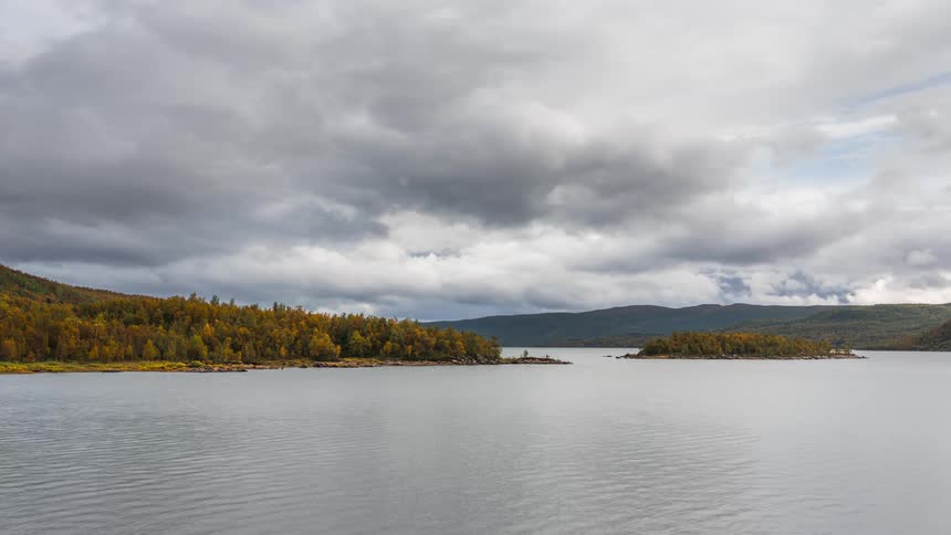 An island and a coast of a land and there is a huge dark side and cloud passing in the sky