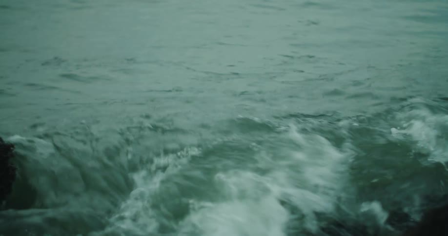 Continuous moving sea water hitting black rocks