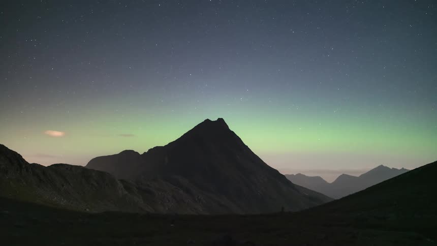 Landscape with rocky mountains and a greenish sky with aurora borealis in light teams