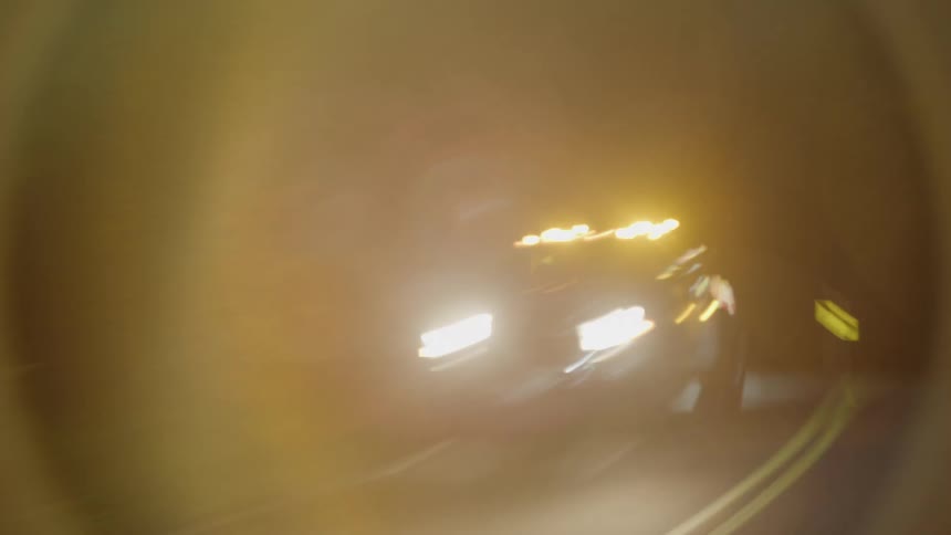 Vehicle with high beams stopped in the middle of a road at night