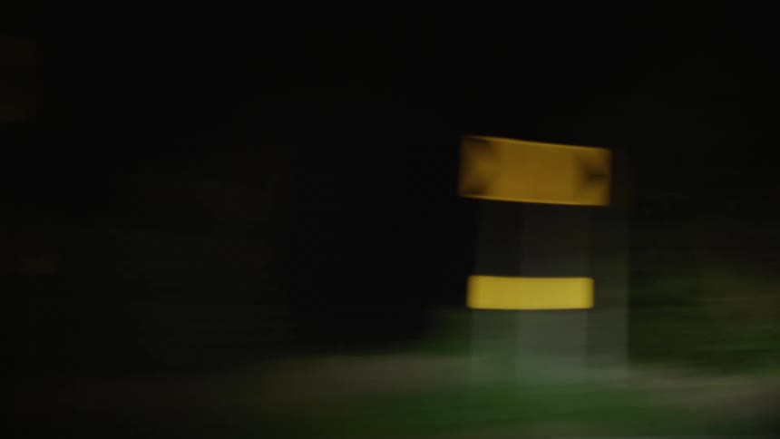 Rural highway curves past arrow signs at night