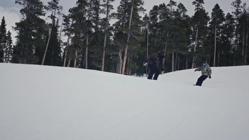 People on a mountain walking and doing snowboarding tricks