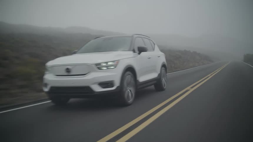 Vehicle drives away from mountains on a foggy day