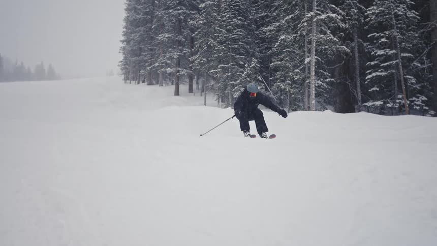 Person snowboarding down a mountain on a snowing day