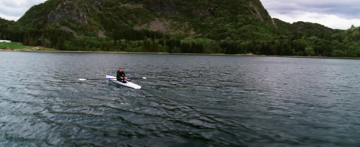 Man rows on the lake near a treecovered mountain