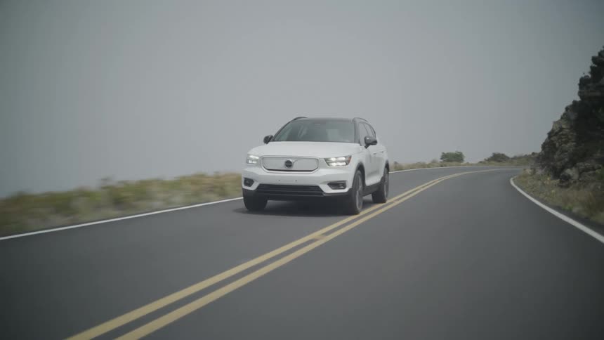 A car driving along a road on the side of a mountain on a cloudy day