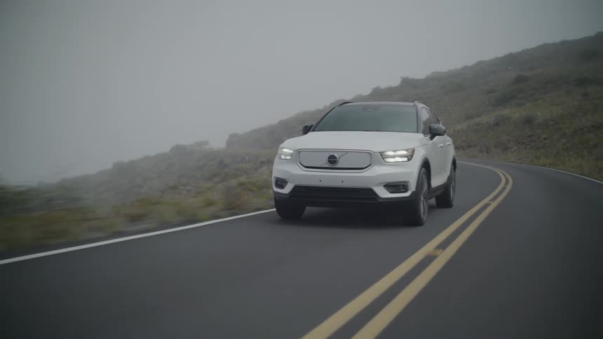 A car drives on a road near hilly terrain