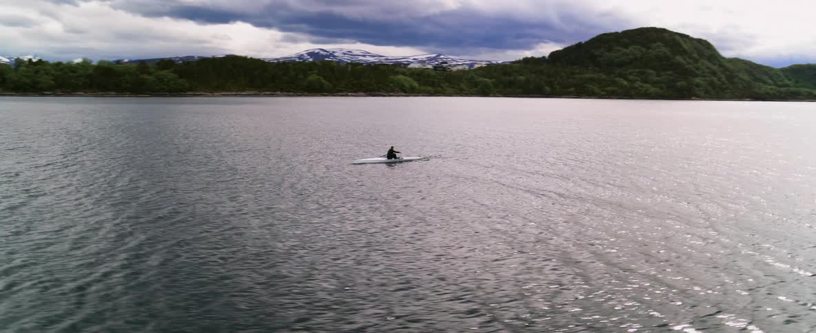 Man rowing a boat on the sea with the pink and blue hues at sunset