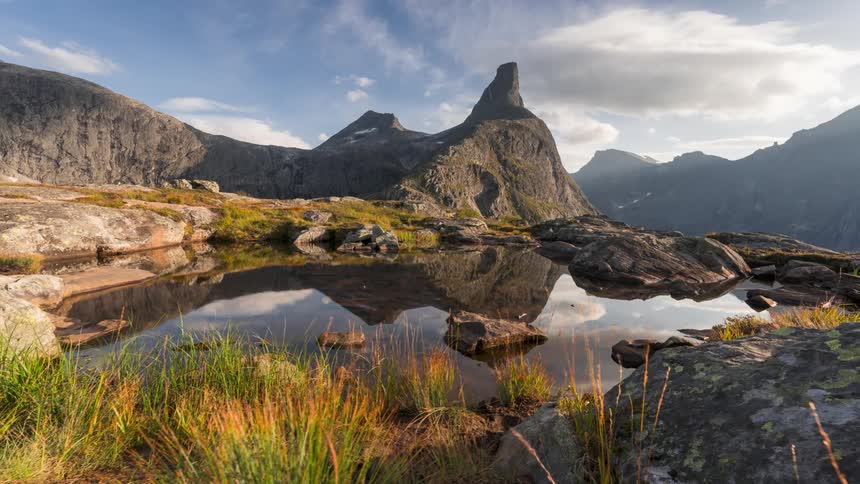 Beautiful landscape of a lake and a mountain surrounded by rocks with blue sky measurements and clouds passing by in light time