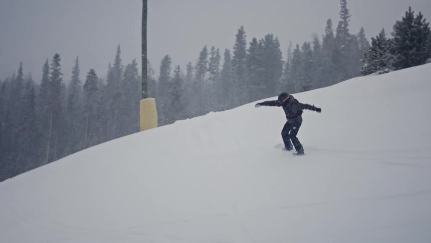 Person doing a small snowboard maneuver in the middle of the mountain on a day begins