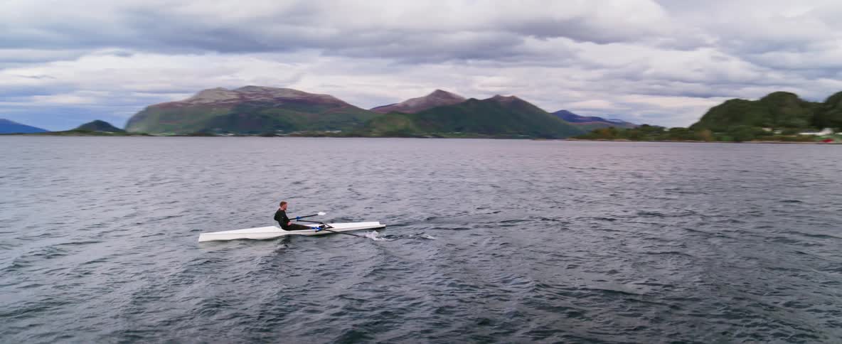 Aerial orbit shot of an athlete training on a cloudy day in the open water