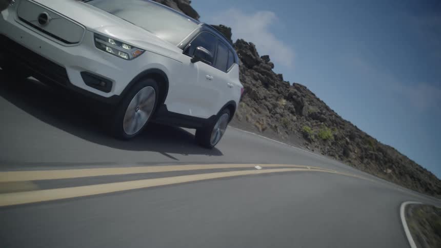 A white car driving on an asphalt street in a rural region