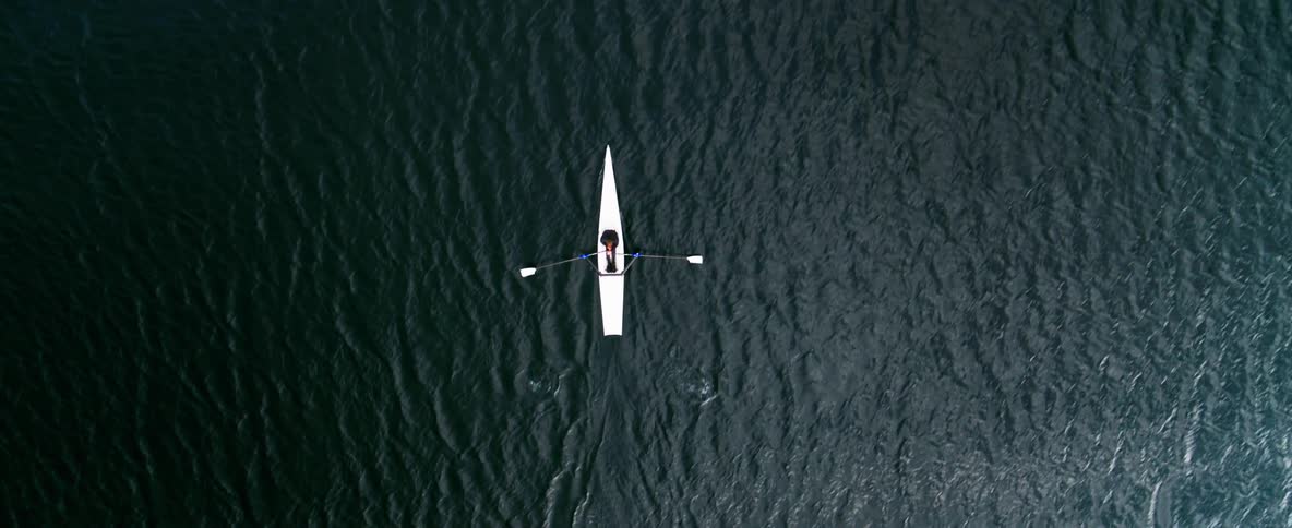 Top-down tracking shot of a sea kayak as it makes its way across the blue water