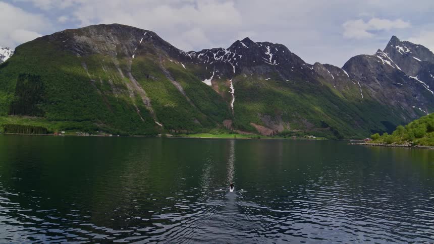 Soaring aerial of Norway's fjords with a solitary rower making his way across an inlet