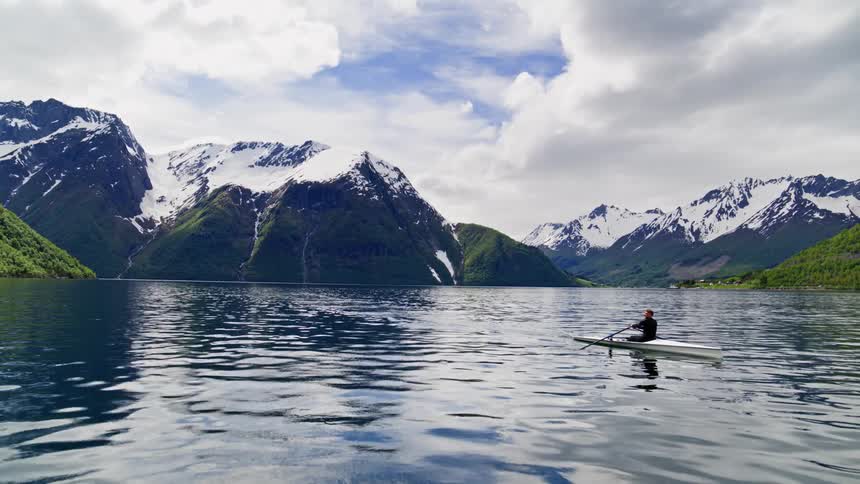 Majestic naturescape in Norway on the fjords shows a kayaker taking in the dreamlike setting