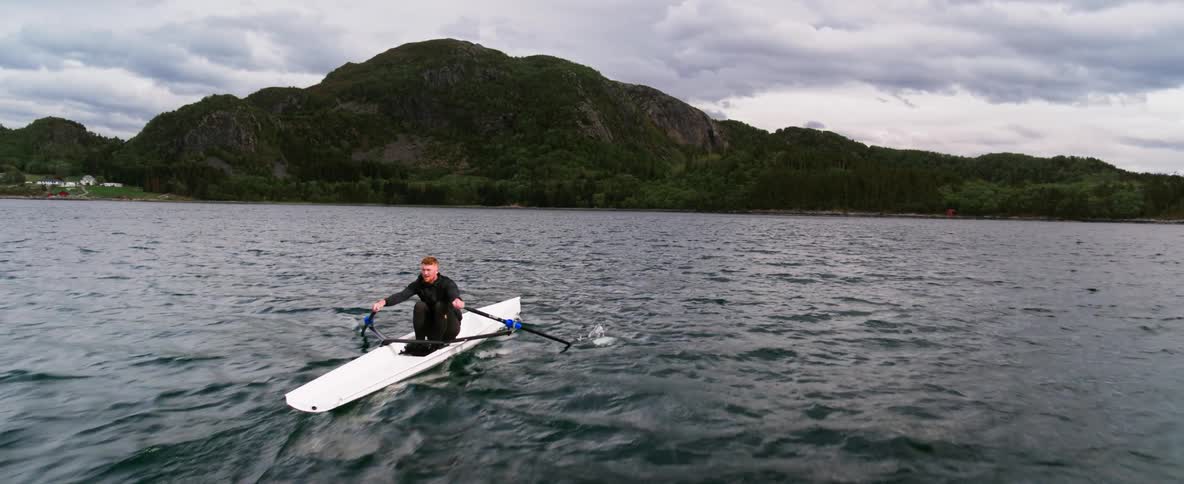 Rowing athlete shows grit and determination training in his boat on rough water