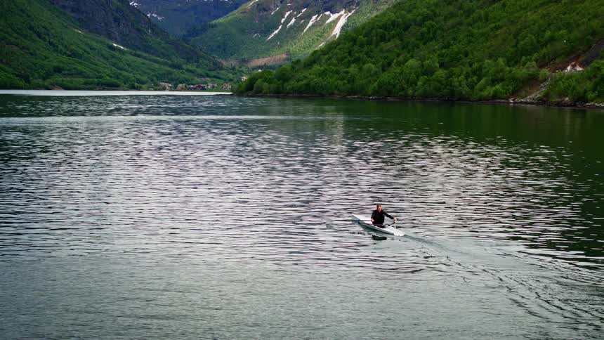 A man meditates rowing his boat in a stunning landscape