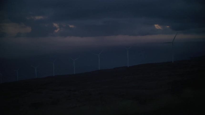 Landscape on a dark morning with wind power engines moving through the mountains
