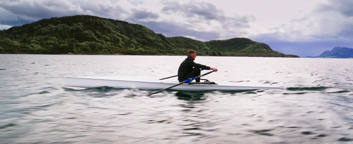 A man rows a kayak in the open sea at sunset