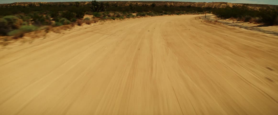 Point of view of a desert dirt road on a blue sky day