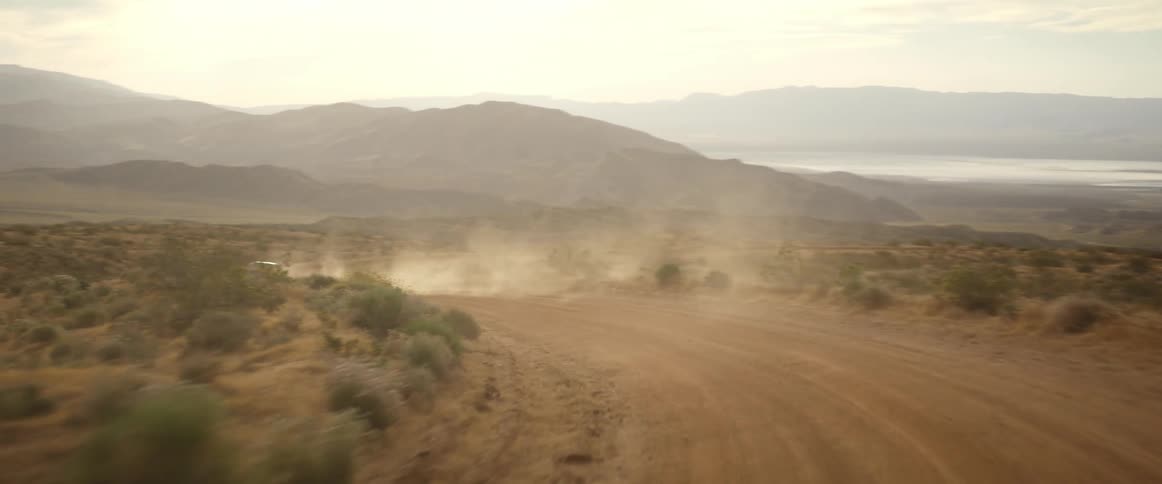 A vehicle drives on a desert road