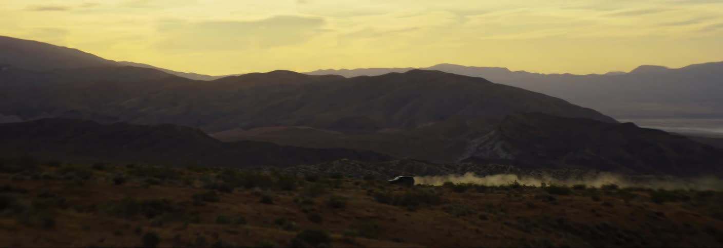 A car drives on a road in a desert