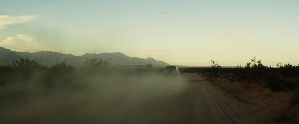 A vehicle running on a sandy road at sunset