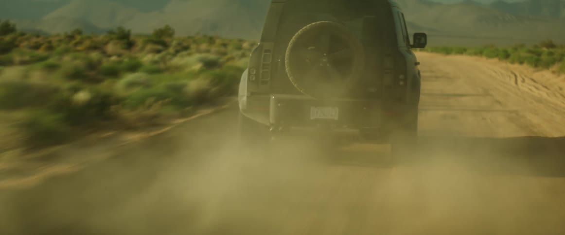 A vehicle races down a road in a desert