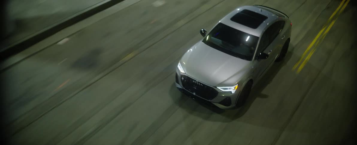 Aerial view of silver car driving in industrial area at night