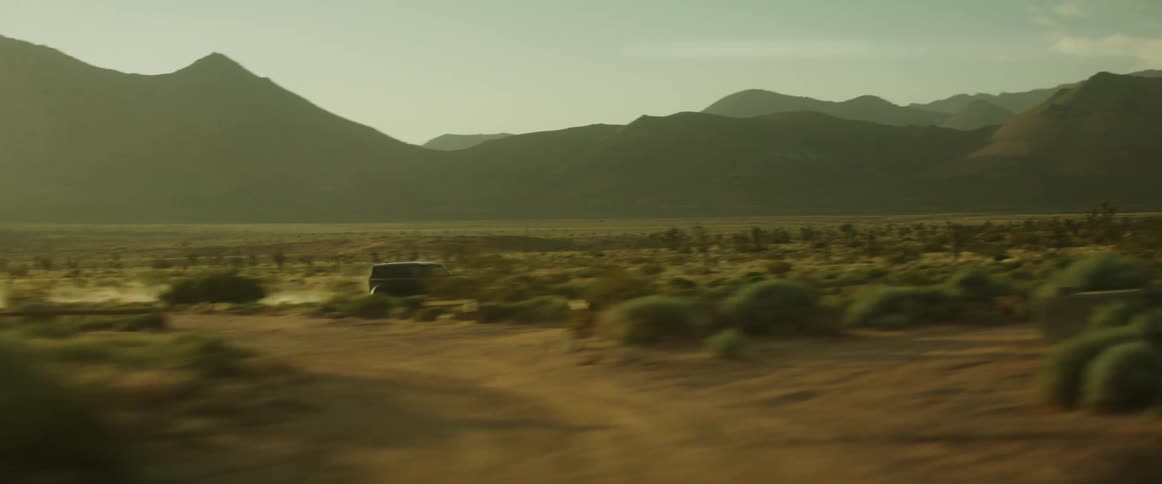 Black jeep speeding along a dirt road in a natural environment with mountains around