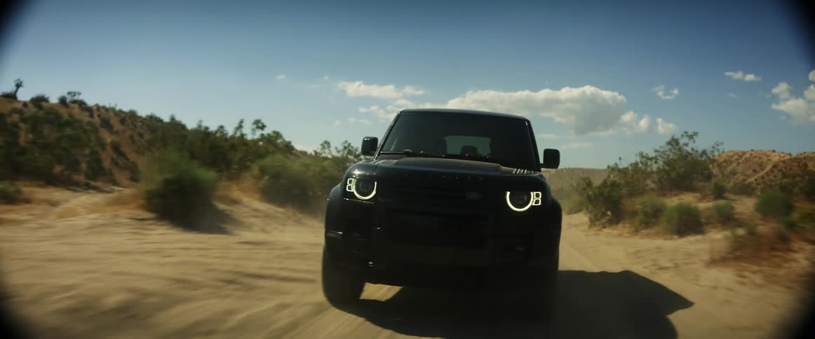 Black jeep entering a dirt road in a desert location at high speed