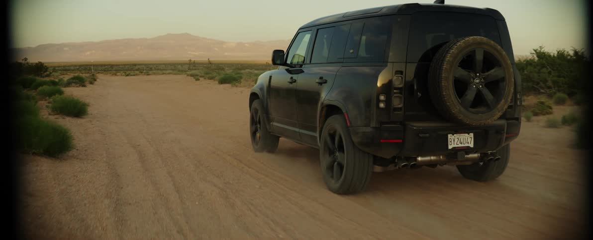 Black jeep traveling along a sandy road in a natural environment with mountains around