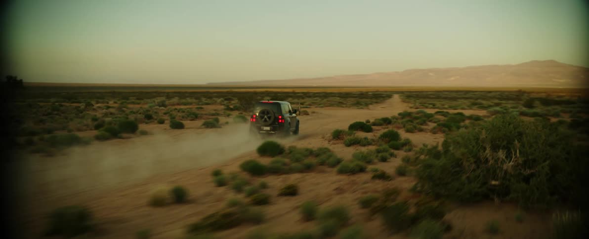 Black jeep speeding along a sandy road in a deserted place