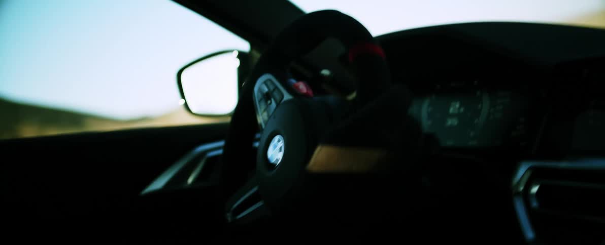 Closeup on the dashboard of a bmw with a persons hands driving and turning with the steering wheel