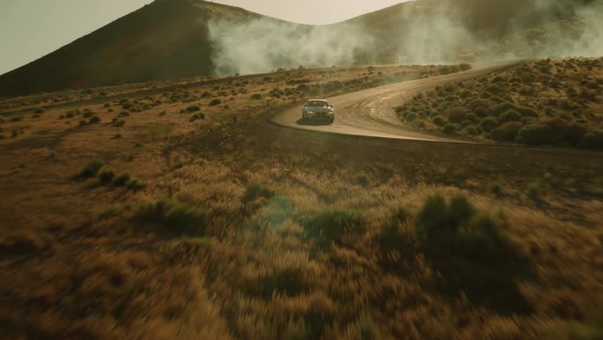 Aerial of a car speeding on a deserted road during the day