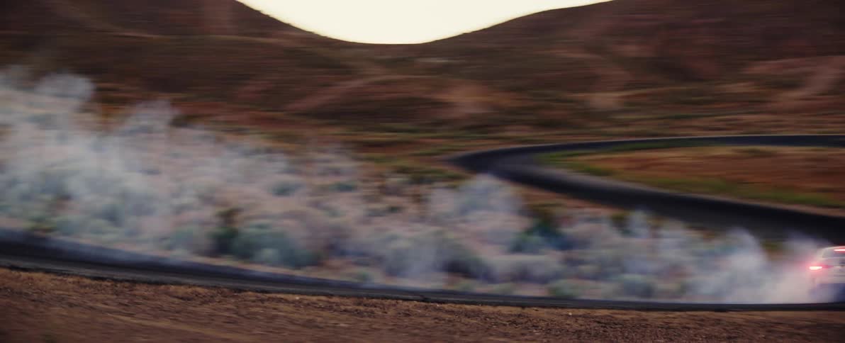 Sports car drives fast and creates smoke on desert road
