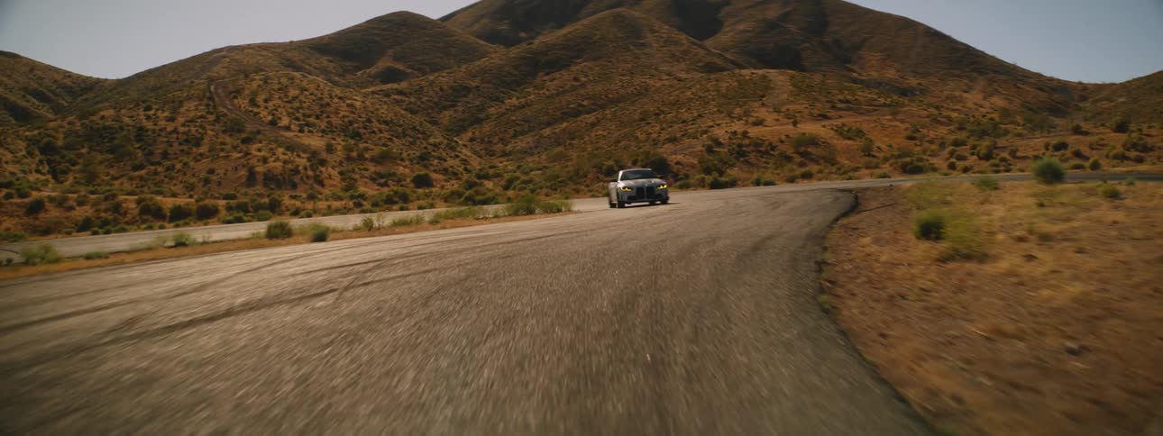 White bmw coupe on a road next to hills and mountains
