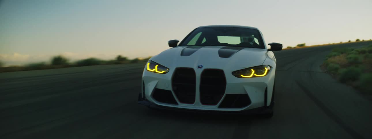Pearl white bmw coup moving along the road next to mountains in the late afternoon