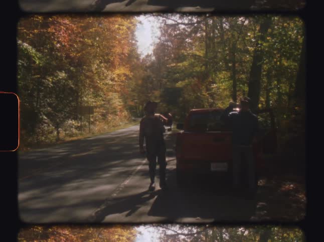Two men picking up accessories from the pickup truck on the side of a forest road