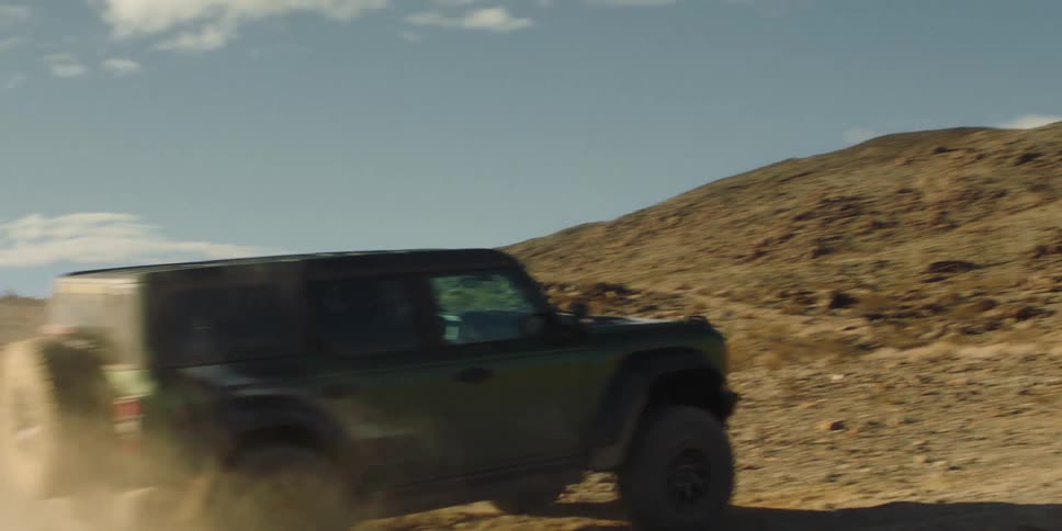 Jeep climbing a slight slope in the middle of desert soil during the day