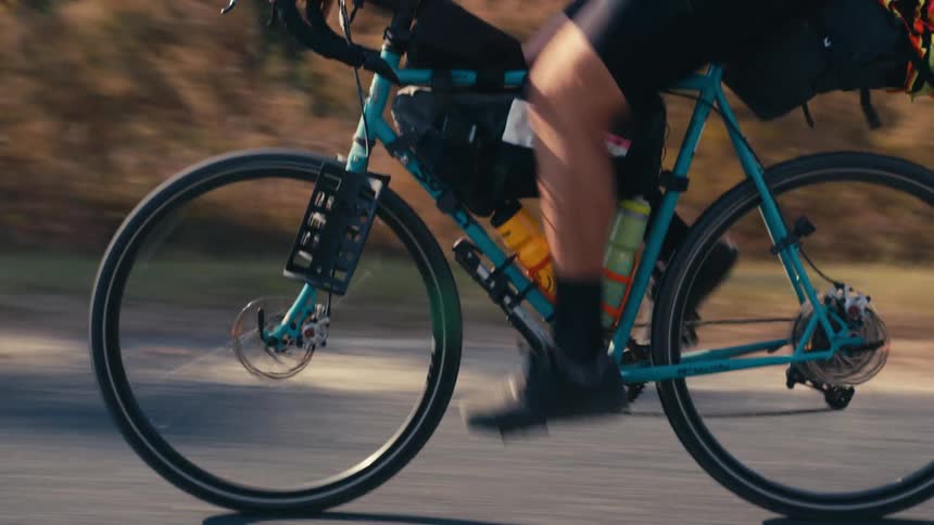 A cyclist pedalling on a road next to a forest