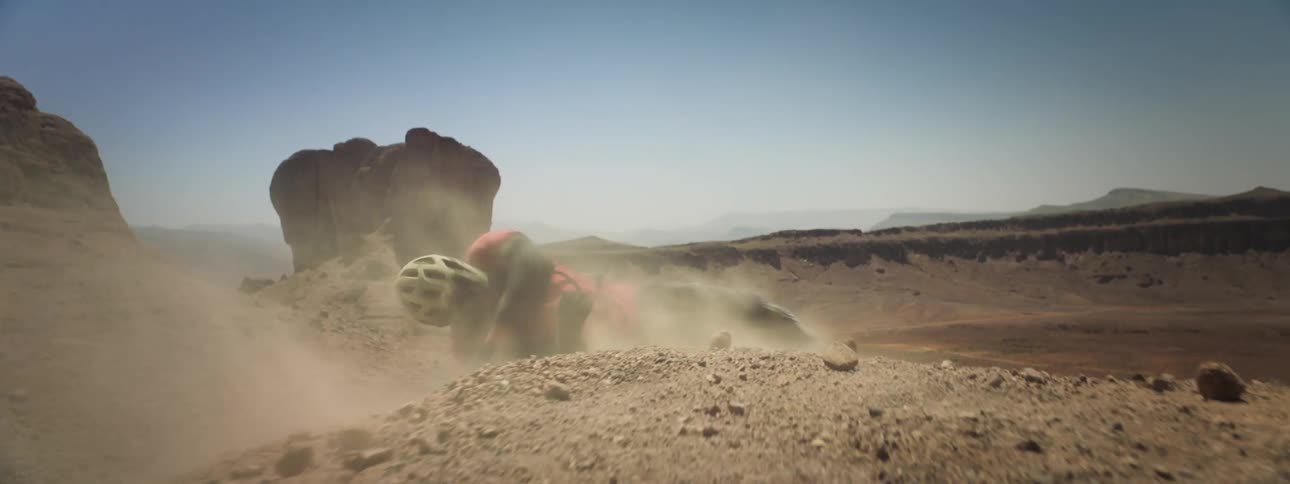 A person is thrown down to the ground and off down a slope in the desert