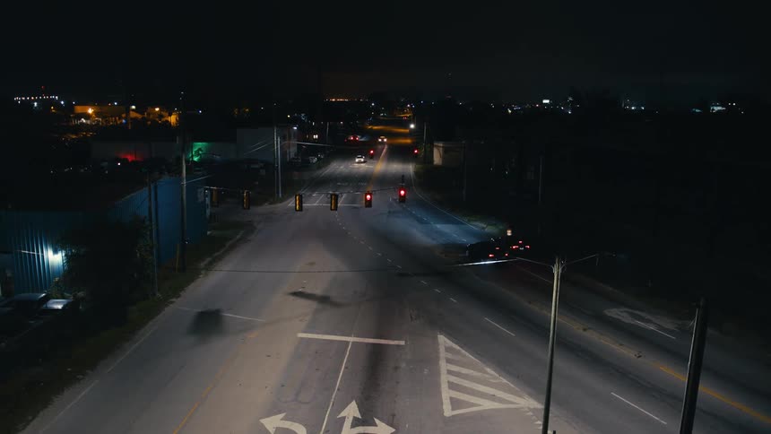 Bicycle rides through intersection with few cars at night