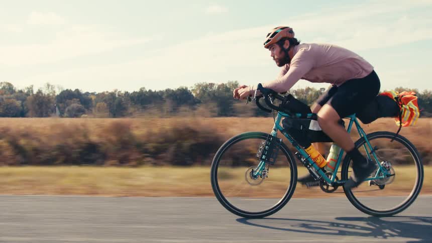 A man is riding his bicycle past the field