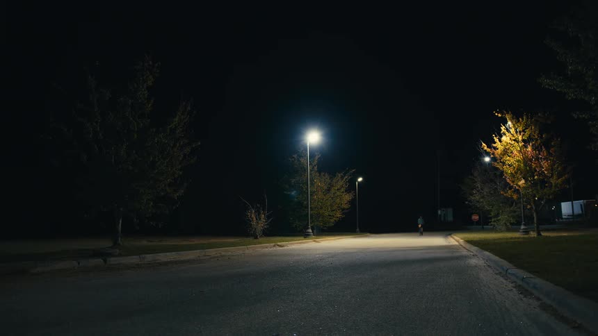 A person driving a bike on a lone street at night