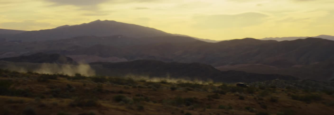 A vehicle drives through a desert