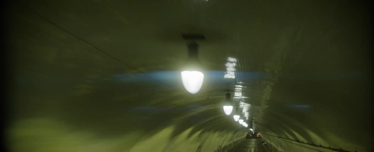 Closeup of the overhead lamps on the ceiling of a vehicular traffic tunnel at night