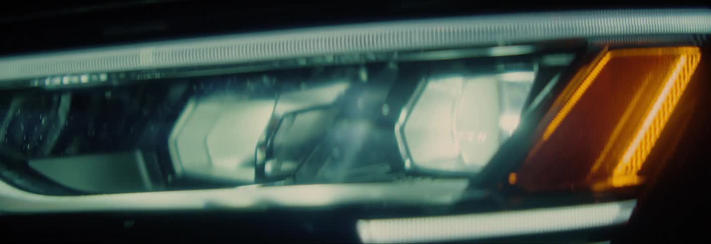 Closeup on the headlight of a moving vehicle at night