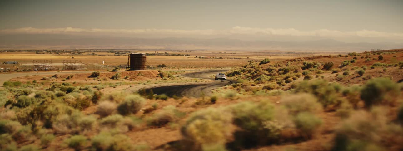 Car driving down a road through brushcovered land
